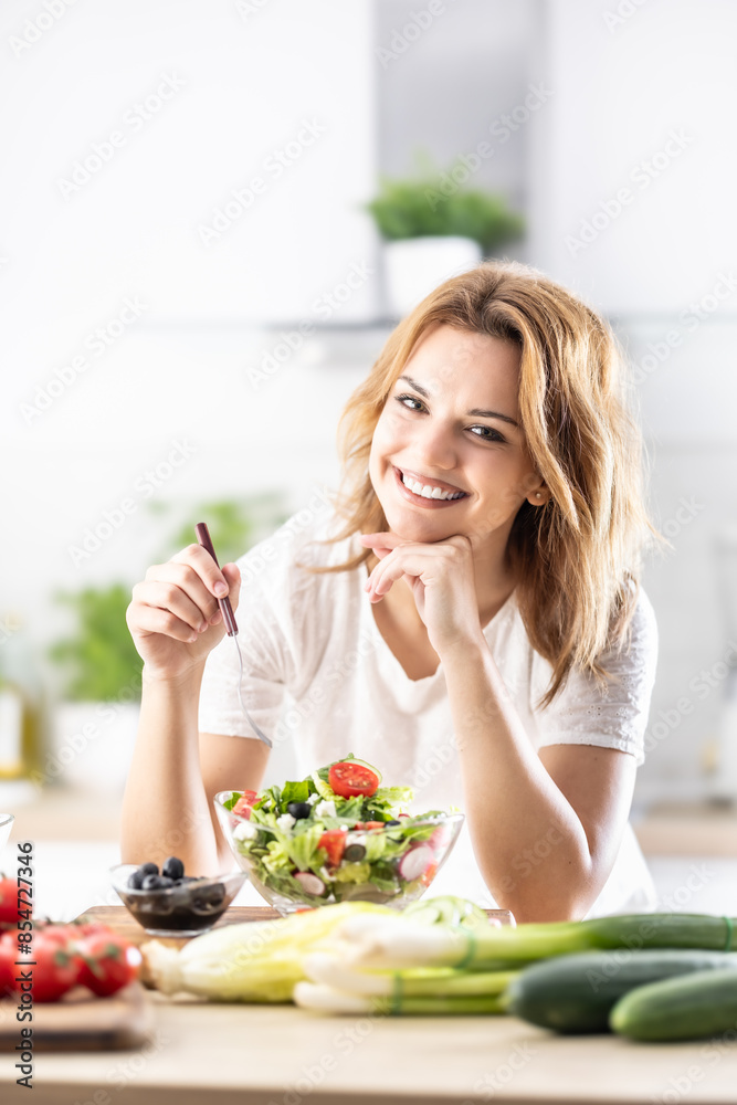 Young cute woman trying healthy vegan vegetable salad at home in kitchen Young cute woman trying healthy vegan vegetable salad at home in kitchen