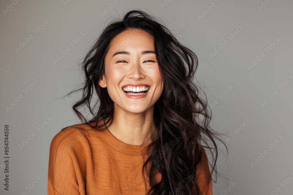 Portrait of a content asian woman in her 30s laughing over soft gray background Portrait of a content asian woman in her 30s laughing over soft gray background