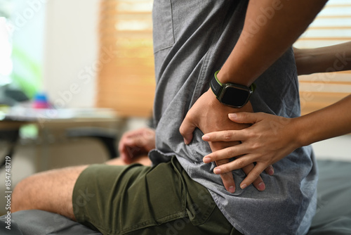 Professional physiotherapist examining male patient with low back lumbar pain. Alternative medicine and rehabilitation concept