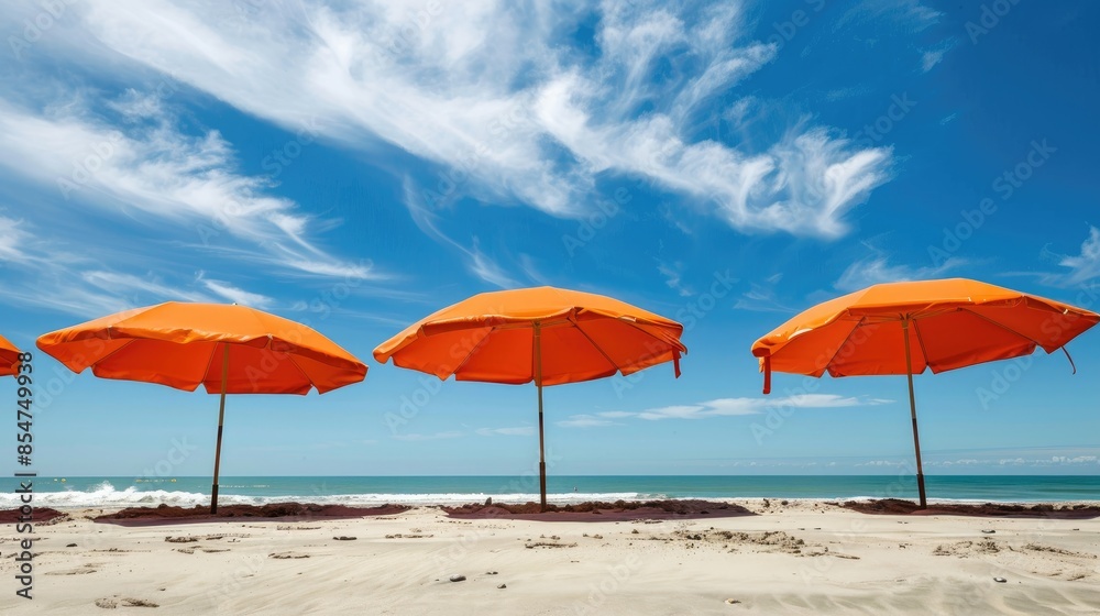 Orange beach umbrellas provide shade under a sunny sky setting a summer vacation atmosphere on the sandy beach Orange beach umbrellas provide shade under a sunny sky setting a summer vacation atmosphere on the sandy beach