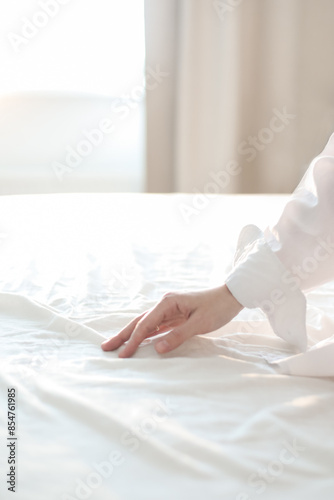 Hand on a soft duvet. Woman touching bed sheets, closeup. Young woman intimacy on bed. Soft, gentle, tender cozy morning concept
