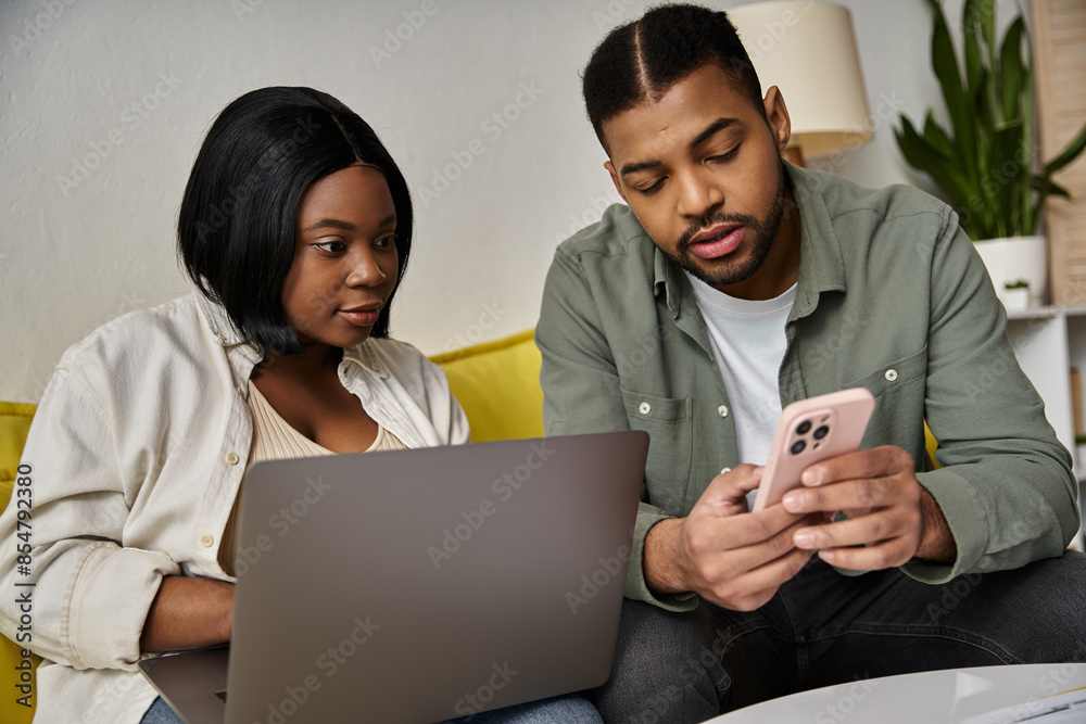 A young African American couple relax at home with laptops and a phone. A young African American couple relax at home with laptops and a phone.