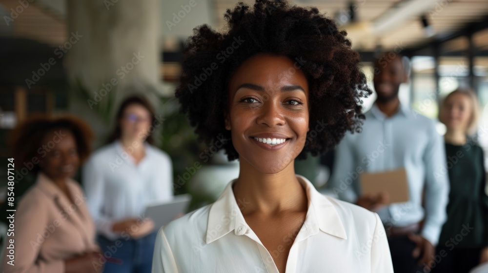 Happy businesswoman standing with her colleagues in a modern office, teamwork, confidence and diversity in the workplace Happy businesswoman standing with her colleagues in a modern office, teamwork, confidence and diversity in the workplace