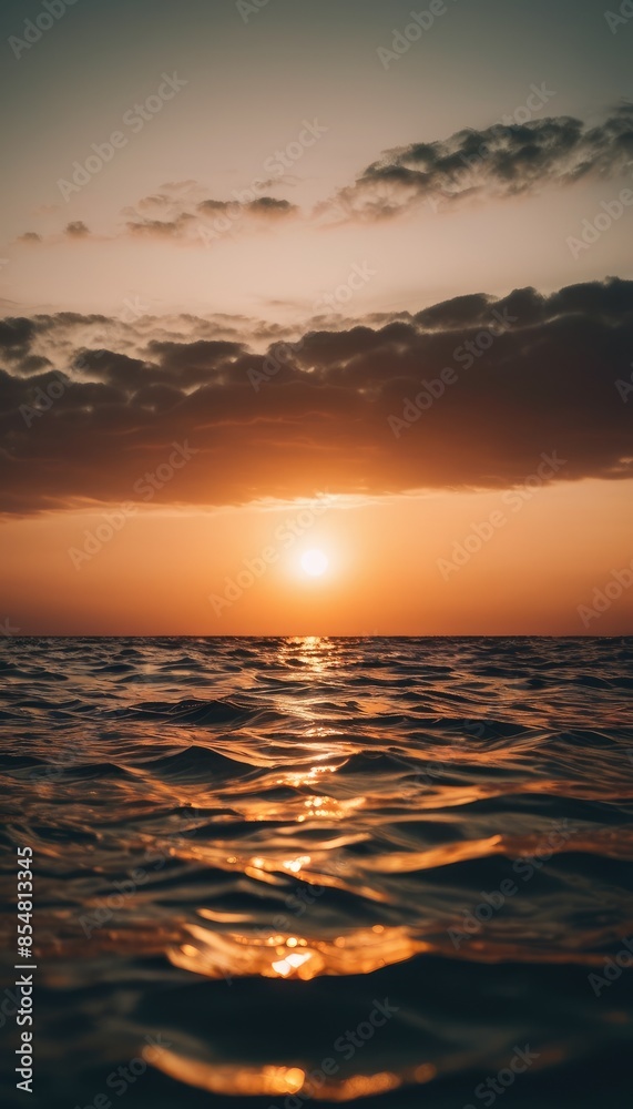 Obraz premium A serene sunset over a calm lake, with the sun casting a golden glow on the water and dark clouds adding contrast to the sky