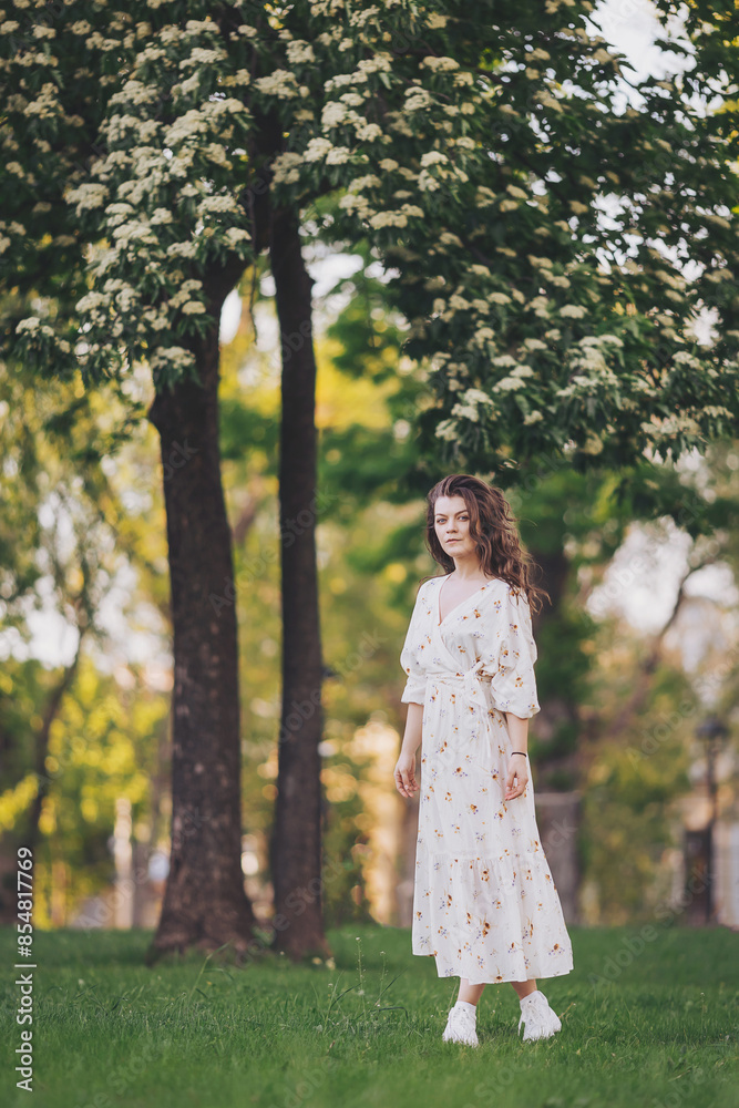 fairy, wonderful summer girl. Beautiful romantic woman, blooming tree on the background. Portrait of beautiful caucasian woman in long white retro dress walking in green summer blossom park. fairy, wonderful summer girl. Beautiful romantic woman, blooming tree on the background. Portrait of beautiful caucasian woman in long white retro dress walking in green summer blossom park.