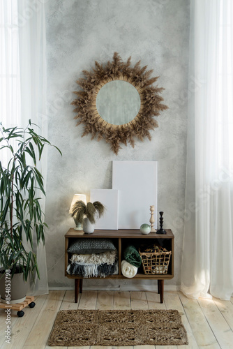Фотография Sunburst mirror above a wooden cabinet filled with blankets and decor