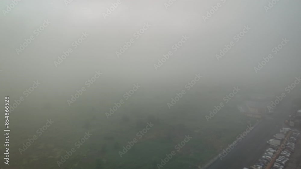 This video shows a foggy view from an airplane window over a city and waterway. The thick fog obscures the details of the landscape below. This video shows a foggy view from an airplane window over a city and waterway. The thick fog obscures the details of the landscape below.