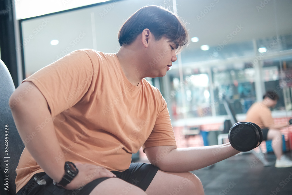 Overweight man lifting dumbbell in gym Overweight man lifting dumbbell in gym