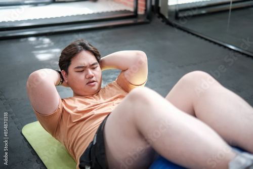 Overweight man doing crunches on exercise mat