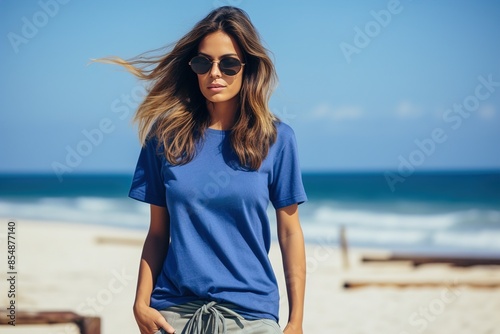 A woman wearing a blue shirt with the number 22 on it stands on a beach