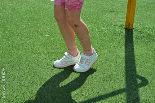 an abrasion on the child's knee, a bruised leg. white sneakers, children's shoes. background for the design.