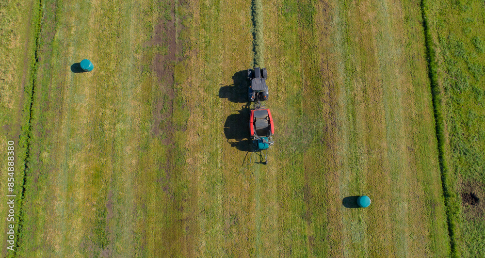 Schwarzer Treker oder Traktor mit einer roten Stroh Festkammerpresse bei der Strohernte auf einem gemähten Feld Schwarzer Treker oder Traktor mit einer roten Stroh Festkammerpresse bei der Strohernte auf einem gemähten Feld