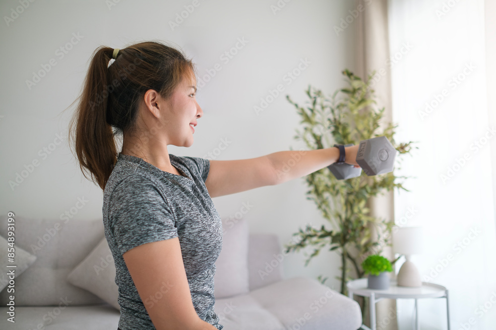 Sporty young woman exercising at home with dumbbells. Sporty young woman exercising at home with dumbbells.