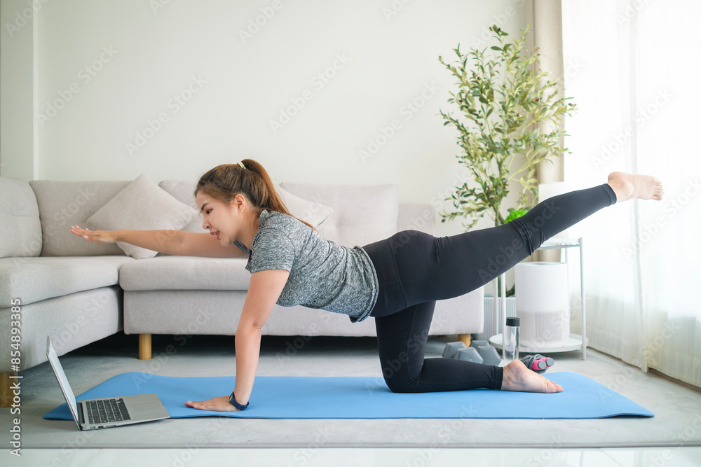 Young Asian woman in sportswear practicing yoga, doing balancing table top pose on mat at home. Young Asian woman in sportswear practicing yoga, doing balancing table top pose on mat at home.