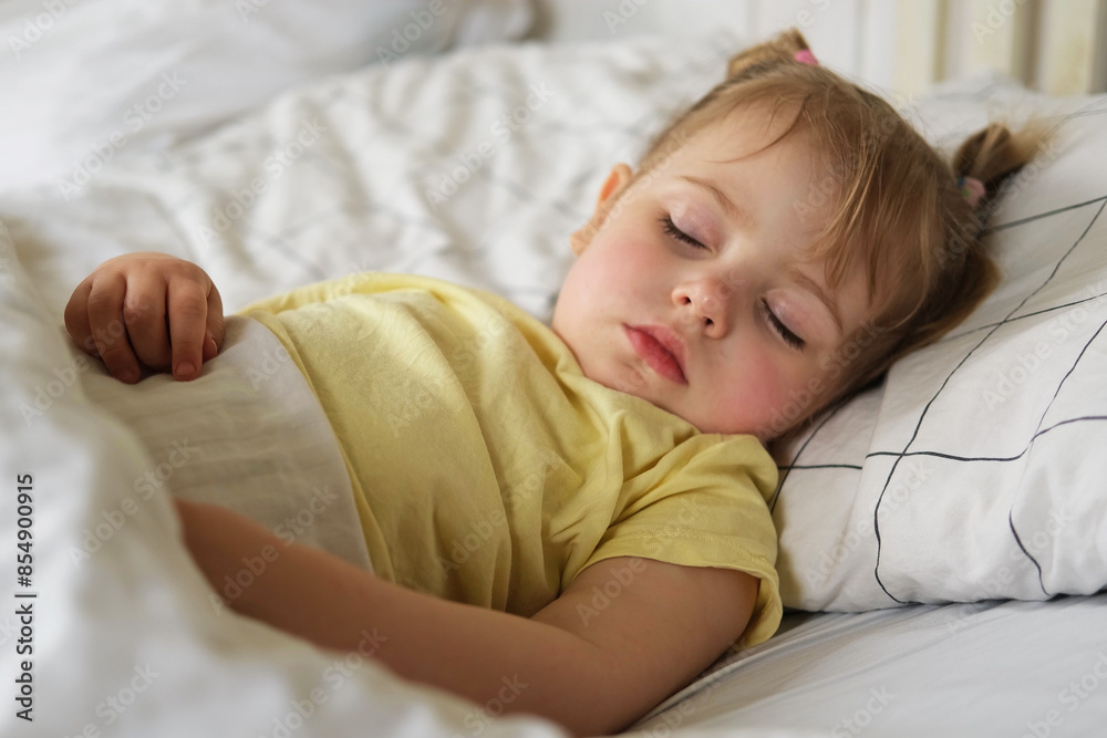 Peaceful adorable baby sleeping on a bed at home. Slumbering little child. Two years old girl sleeps peaceful at domestic room interior background. Serene dream. Cute face close up. Deep kid slumber