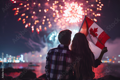 Couple holding Canadian flag watching fireworks by the waterfront at night