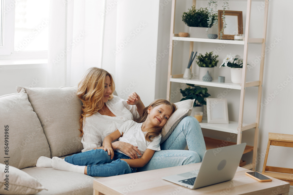 Mother and daughter bonding on a cozy couch, using a laptop, surrounded by a home library filled with books Mother and daughter bonding on a cozy couch, using a laptop, surrounded by a home library filled with books