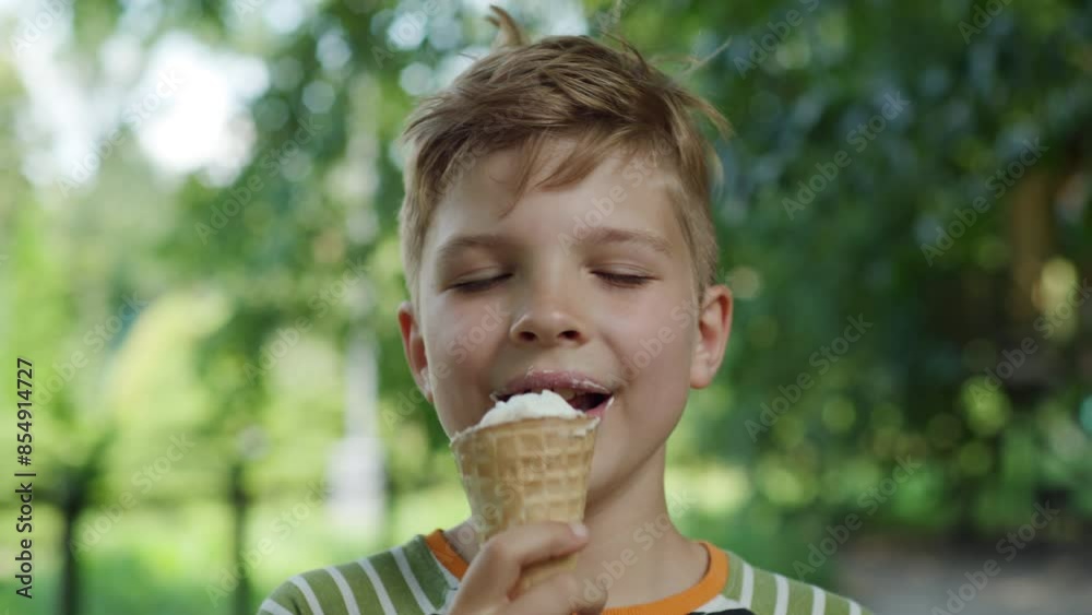 In the warmth of a sunny day, an 8-year-old boy delights in eating ice cream, capturing the simple joys of childhood in a park setting In the warmth of a sunny day, an 8-year-old boy delights in eating ice cream, capturing the simple joys of childhood in a park setting