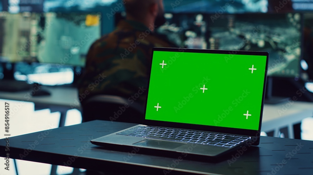 Laptop showing isolated mockup screen in army base of operations, military personnel working on gathering crucial information for a new mission. General headquarters with high tech. Camera A. Laptop showing isolated mockup screen in army base of operations, military personnel working on gathering crucial information for a new mission. General headquarters with high tech. Camera A.