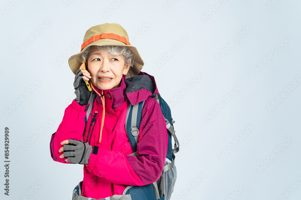 怯えてスマホで通話する登山服のシニア女性 怯えてスマホで通話する登山服のシニア女性