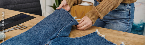 Fotografi A woman cuts and upcycles a pair of jeans for sustainable fashion