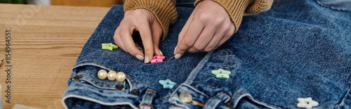A woman decorates jeans with beads.