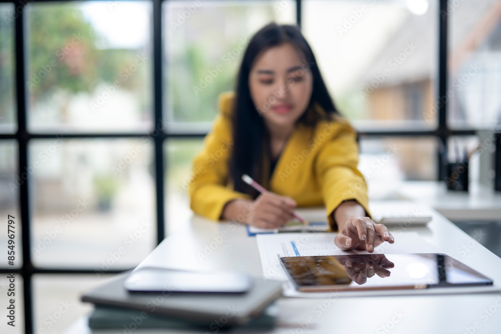 A woman in a yellow jacket is writing on a tablet A woman in a yellow jacket is writing on a tablet
