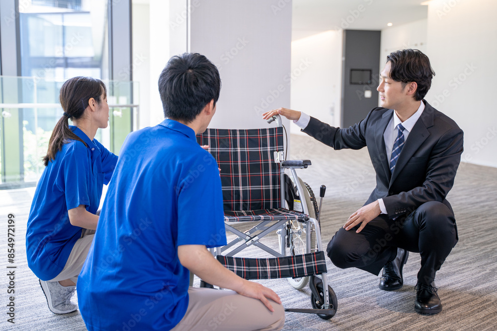 車いすの説明をするビジネスマンとケアスタッフ 車いすの説明をするビジネスマンとケアスタッフ