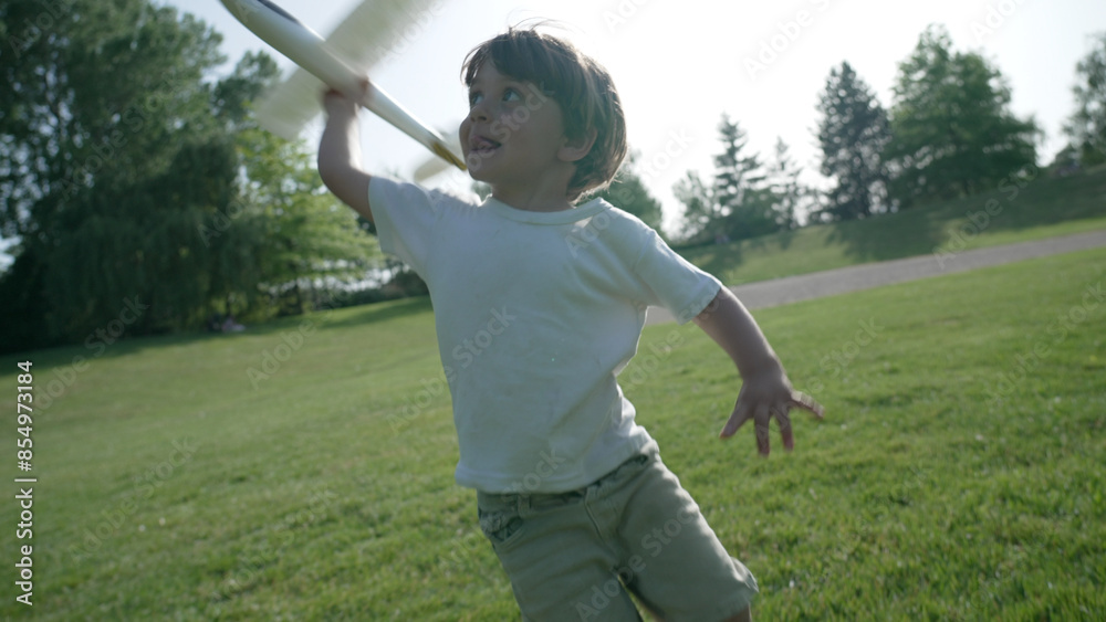 Joyful Child Playing with a Model Airplane in a Sunlit Park Joyful Child Playing with a Model Airplane in a Sunlit Park