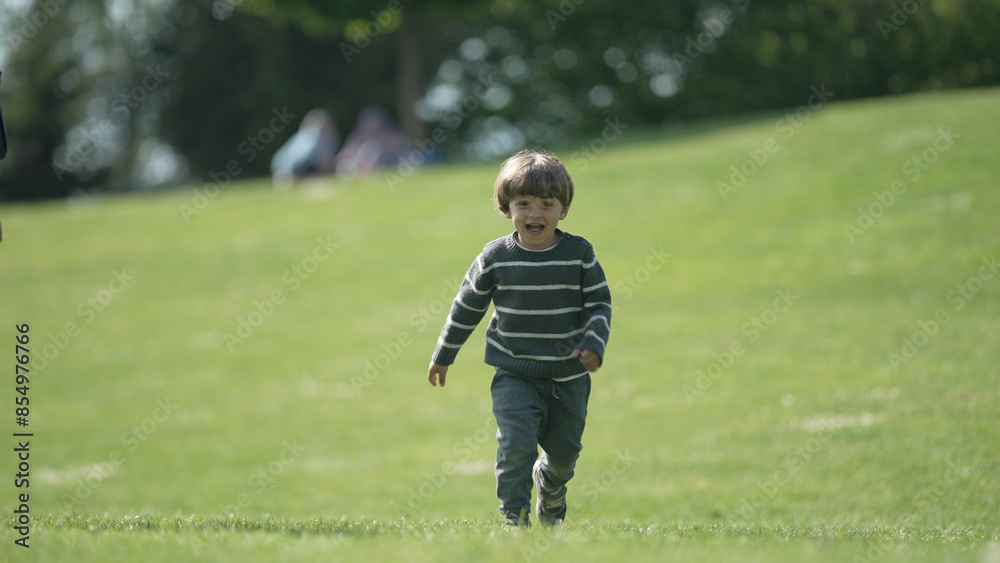 Joyful Young Boy Running Freely Across Lush Green Park, Bright Sunny Day Enhancing the Vibrant Outdoor Setting Joyful Young Boy Running Freely Across Lush Green Park, Bright Sunny Day Enhancing the Vibrant Outdoor Setting