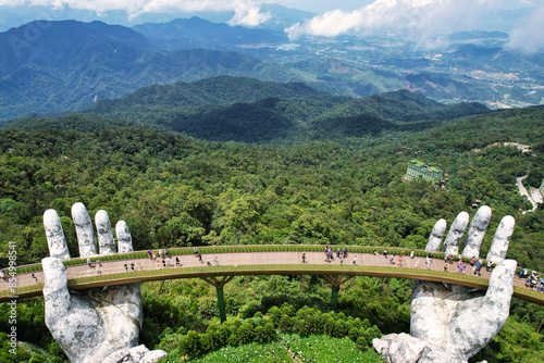 Statue of hands holding a bridge over a forest, towering over landscape Vietnam Da Nang Ba Na Hills Asia photo