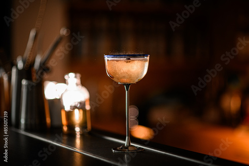 On the bar stands a glass with a tall metal stem