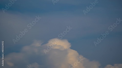 Clouds roll building and receeding into nothing on pastel sky glowing with a tint of yellow photo