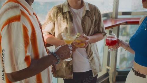 Cropped shot of unrecognizable group of people spending weekend together in trendy bar with refreshing cocktails