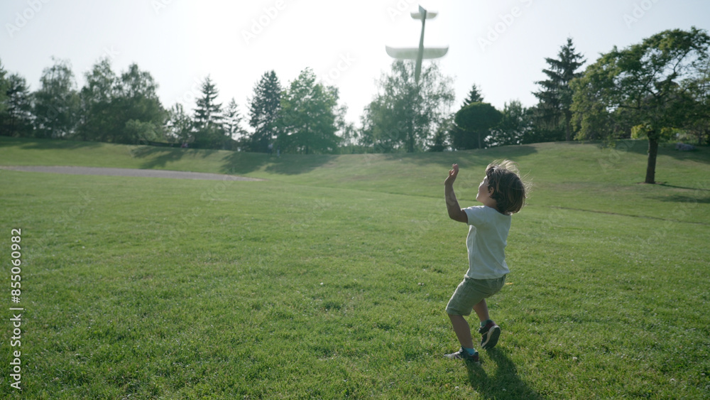 Young Boy Playfully Running with a Toy Airplane in a Lush Park Young Boy Playfully Running with a Toy Airplane in a Lush Park