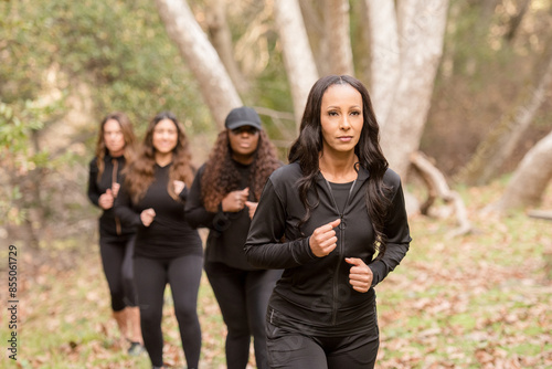 Four women training and running through the woods