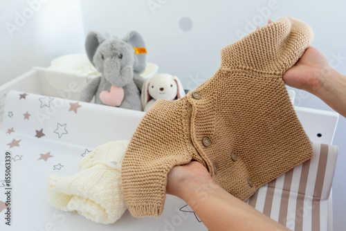 Mom Arranging Neutral Infant Sweater for Storage