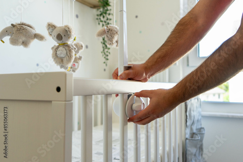 Expectant Father Putting Together Crib with Baby Mobile