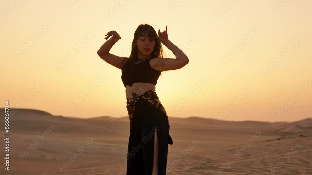 Smiling Asian woman dancing in the Sahara Desert at sunset