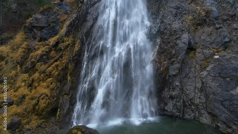 Close-up and tilt-up aerial shot of a dramatic waterfall cascading down a rugged cliff surrounded by the natural rugged terrain and lush greenery. Cascade de la Pissevache, Switzerland. Drone shot 4K Close-up and tilt-up aerial shot of a dramatic waterfall cascading down a rugged cliff surrounded by the natural rugged terrain and lush greenery. Cascade de la Pissevache, Switzerland. Drone shot 4K