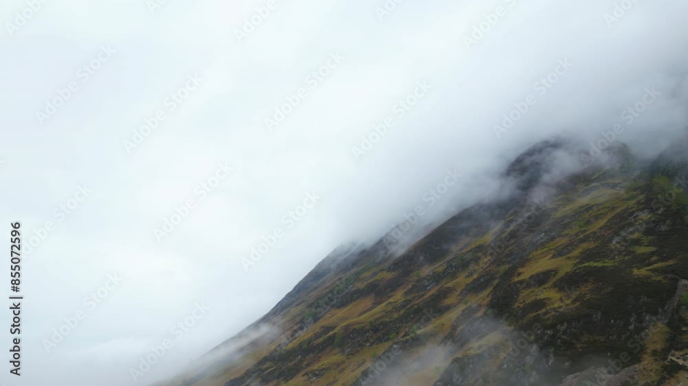 Scene with mountainside in dense clouds, Glen Coe, Scotland. Aerial forward