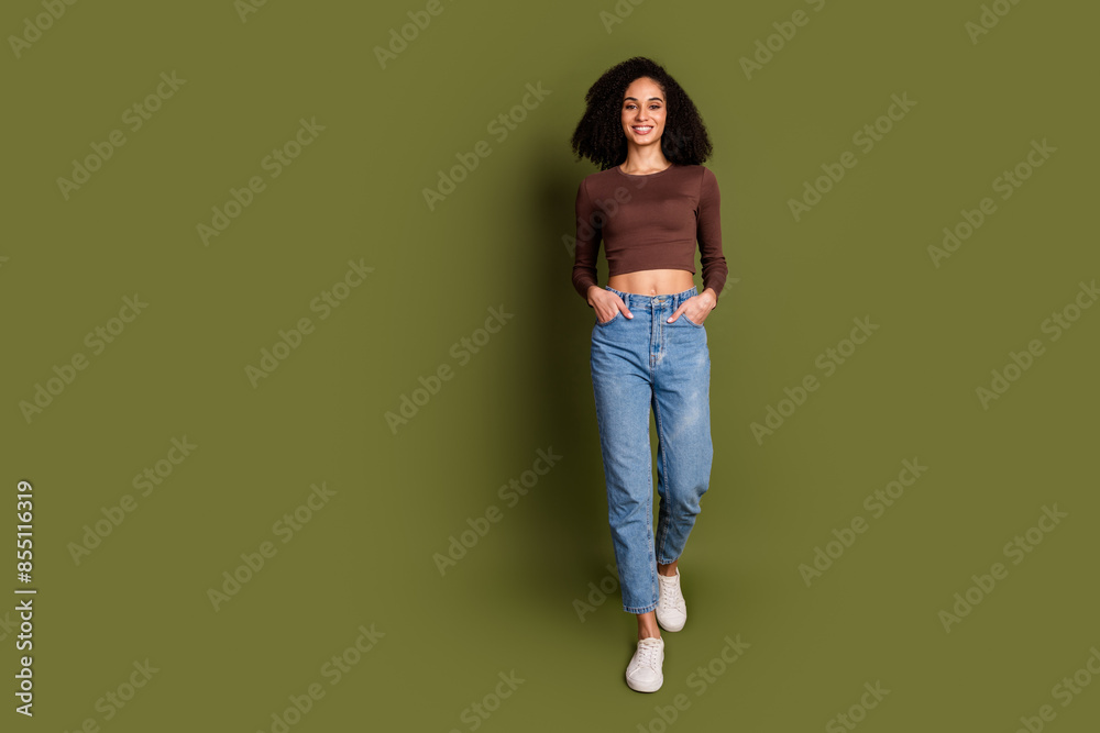 Full size photo of pretty young girl walking posing hands pockets wear trendy brown outfit isolated on khaki color background Full size photo of pretty young girl walking posing hands pockets wear trendy brown outfit isolated on khaki color background