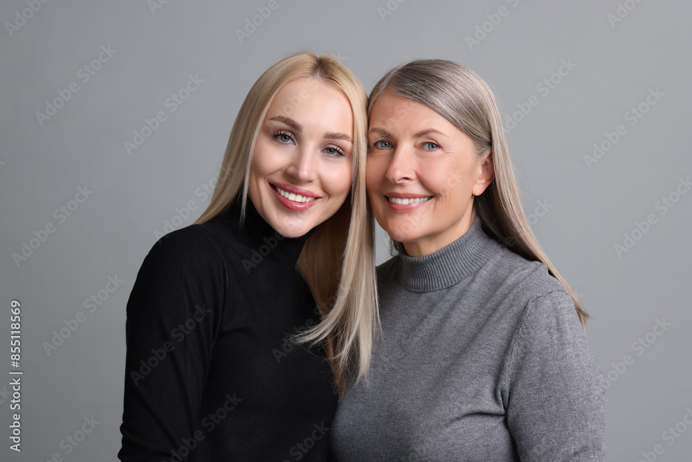 Family portrait of young woman and her mother on grey background Family portrait of young woman and her mother on grey background