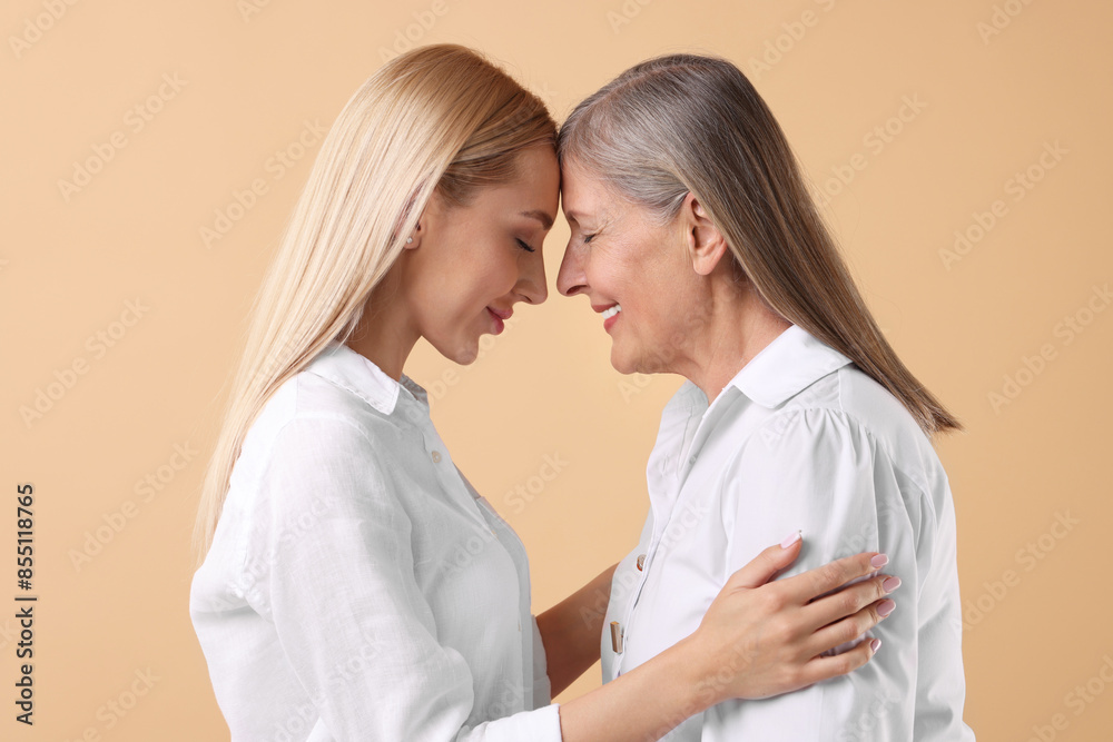 Family portrait of young woman and her mother on beige background Family portrait of young woman and her mother on beige background