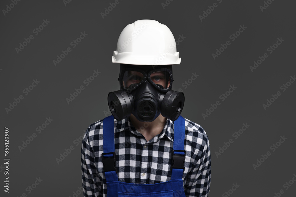 Worker in gas mask and helmet on grey background Worker in gas mask and helmet on grey background
