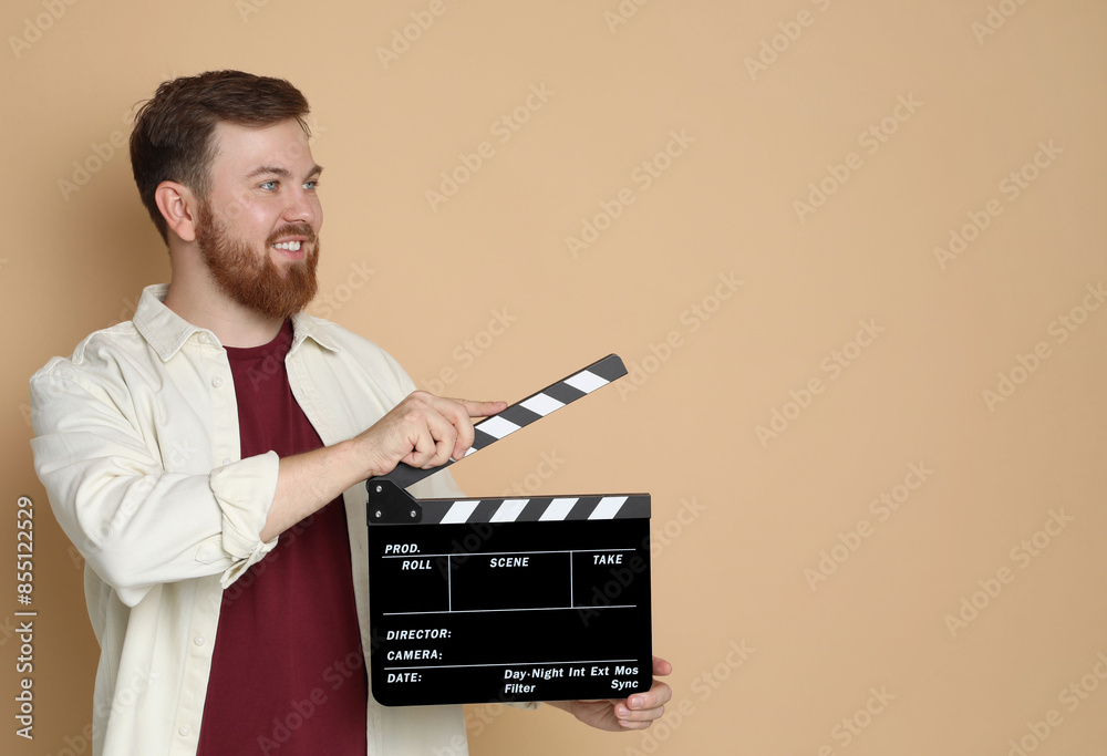 Making movie. Smiling man with clapperboard on beige background. Space for text Making movie. Smiling man with clapperboard on beige background. Space for text