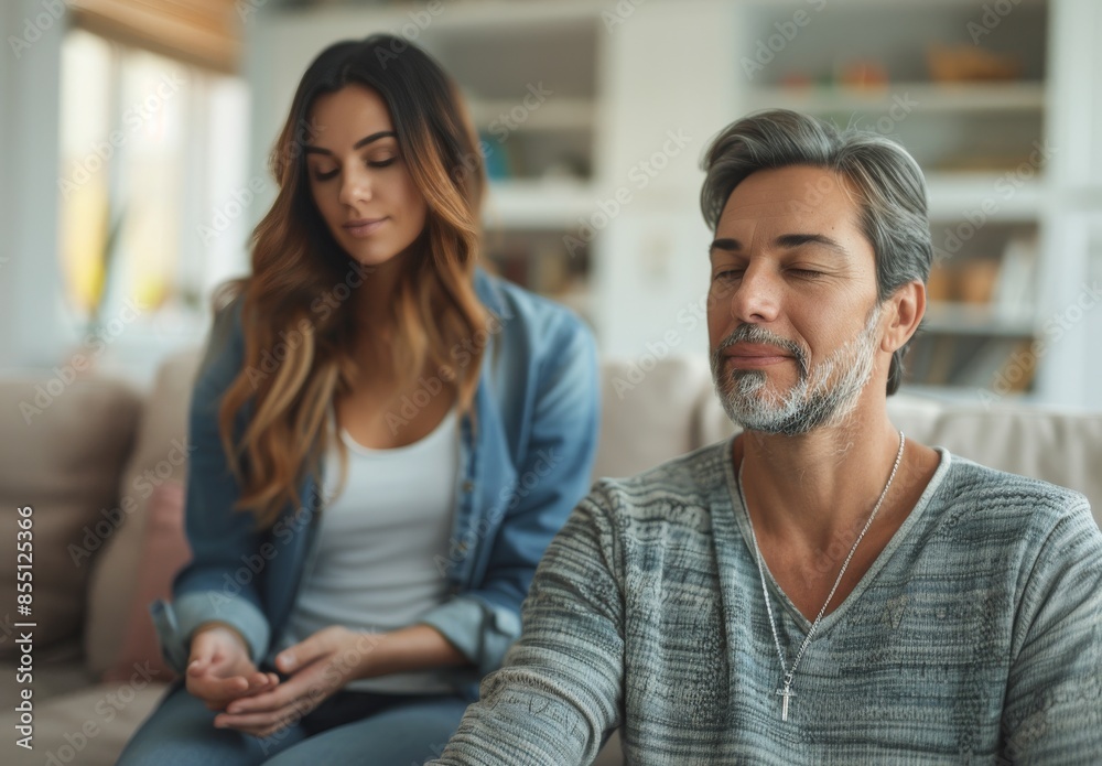 Man Meditating With Eyes Closed While Woman Sits Beside Him on a Couch
