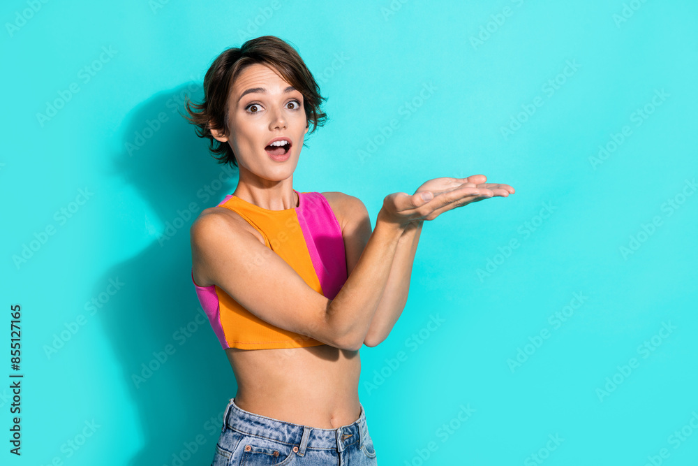 Photo of cute impressed lady dressed colorful top showing two arms empty space isolated turquoise color background Photo of cute impressed lady dressed colorful top showing two arms empty space isolated turquoise color background