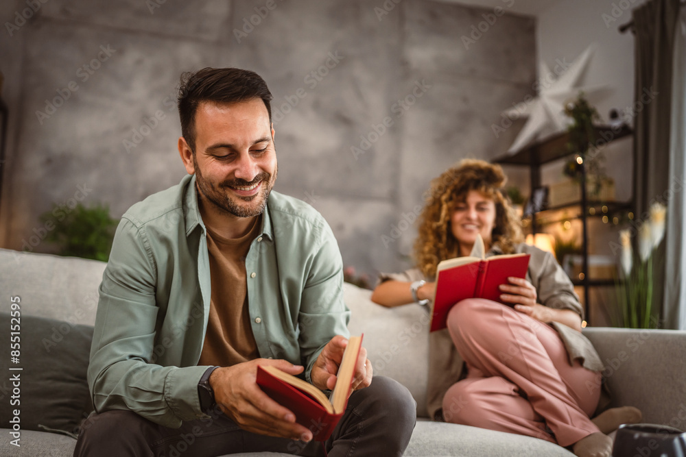 Obraz premium Boyfriend and girlfriend sit on sofa read book and discuss about that