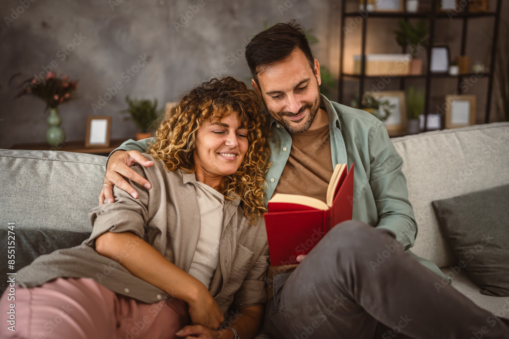 Boyfriend read a book while his girlfriend hug him at home Boyfriend read a book while his girlfriend hug him at home